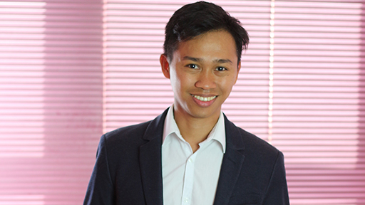 Dennis smiles to camera, wearing a dark suit 