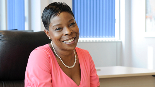 Grace sits at a desk and smiles to camera